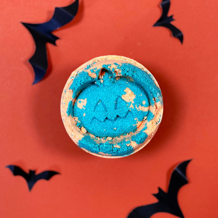 Blue and gold bath bomb with bat designs on an orange background