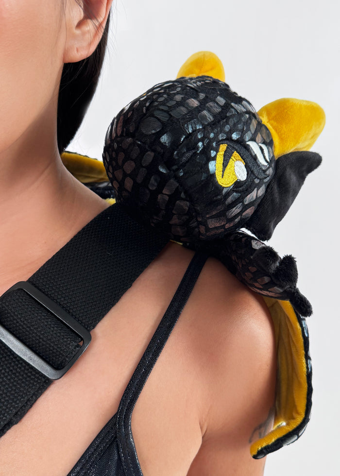 Sleepyville Critters Black Dragon Plush Sling Backpack in black gold with 3D dragon plush and wing detail on rave festival sling backpack — model face view