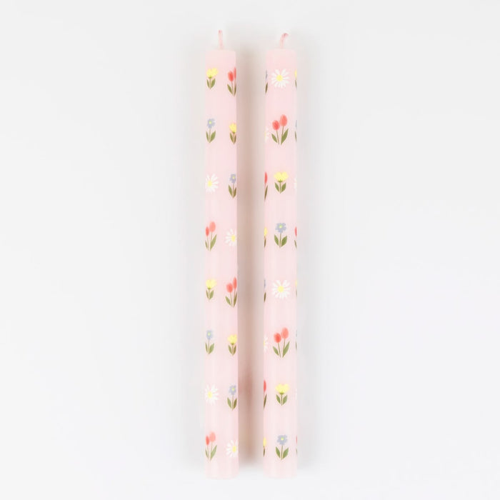 Two pink candles with floral patterns on a white background