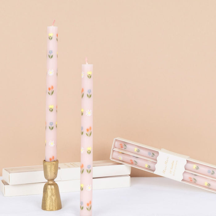 Tall pink candles with floral patterns on a beige background