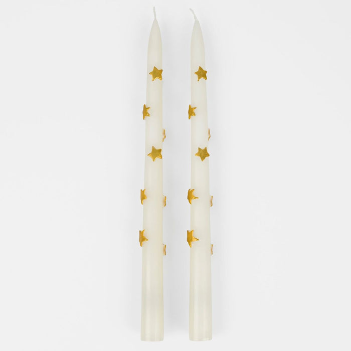 Two white candles with gold star patterns on a white background