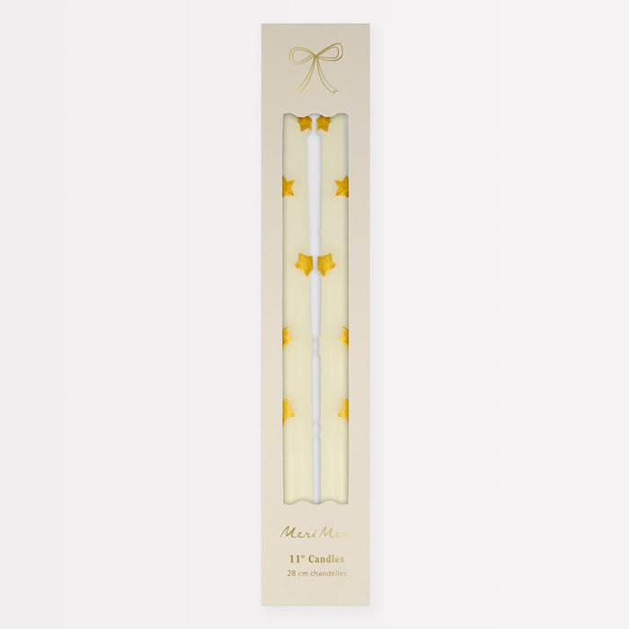 Two white candles with gold stars in a decorative box on a light beige background