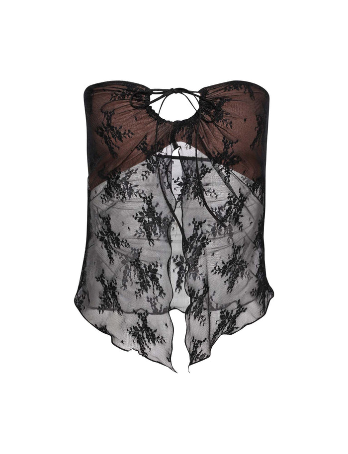 The KAROLINA TOP - BLACK by TIGERMIST is a strapless sheer lace top featuring an intricate floral pattern. It has a keyhole opening at the center with a tie-up detail, and its asymmetrical hemline is flowing and slightly ruffled. The fabric is delicate and semi-transparent.