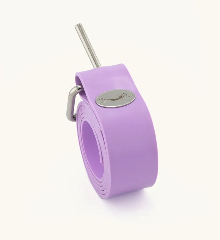 Rolled lavender silicone freediving weight belt with stainless steel roller buckle and Waihana brand logo medallion, displayed on a white background.