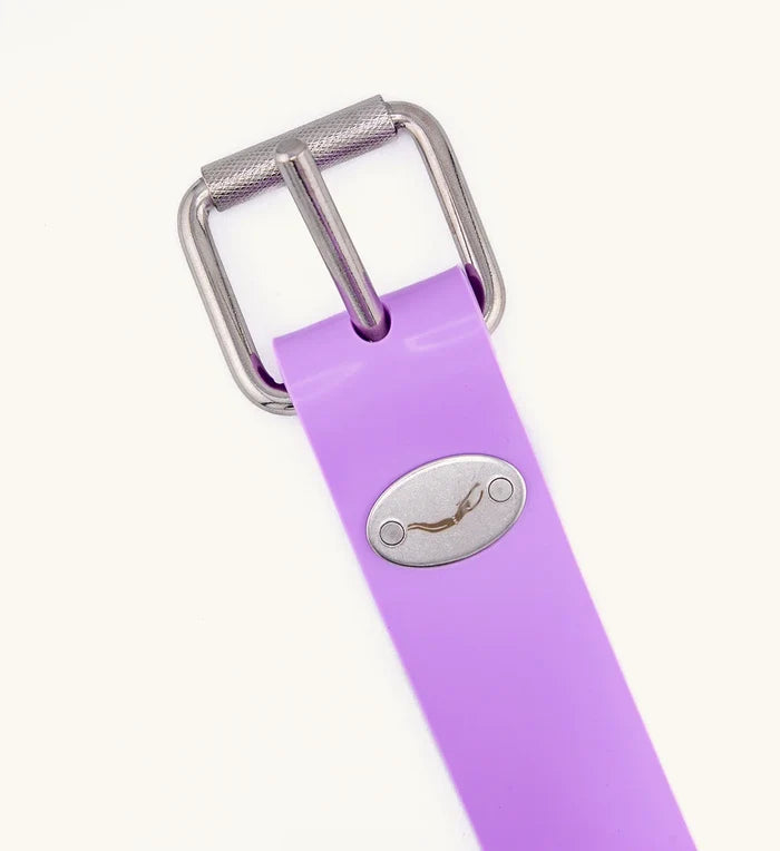 Close-up of a purple rubber freediving weight belt featuring a knurled stainless steel roller buckle and an oval Waihana diver logo medallion, displayed on a white background.
