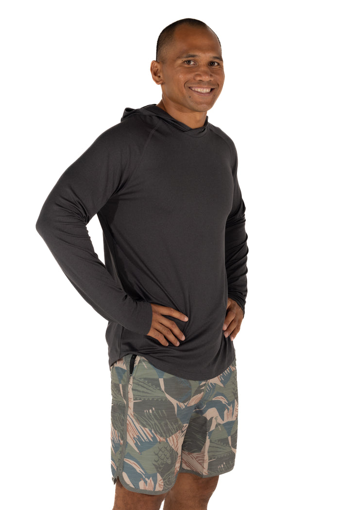 Male model wearing the Waihana Mariner Black Hooded Long Sleeve sun shirt with tropical print board shorts, shown from a slight angle against a white studio background.