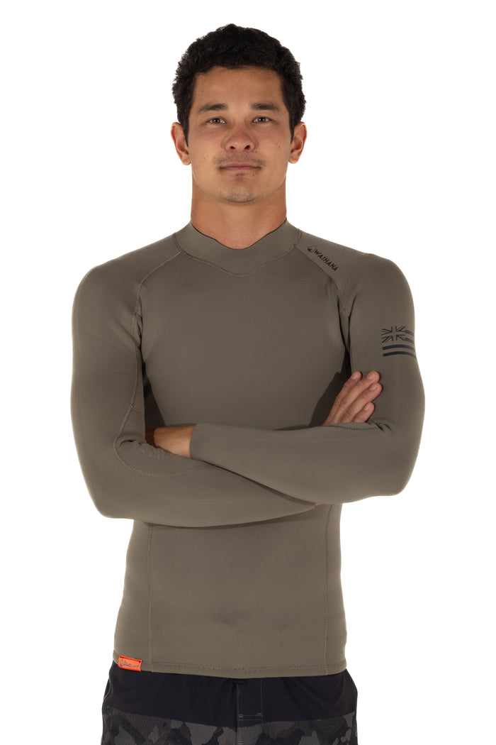 Male model wearing a Waihana Men's Ranger Green long-sleeve rear-zip surf rashguard with Hawaiian flag sleeve graphic, arms crossed against a white studio background.