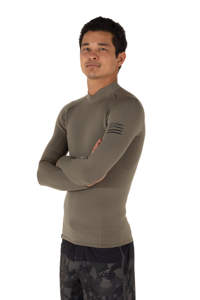 Male model wearing the Waihana Men's Ranger Green long-sleeve surf rashguard top with Hawaiian flag sleeve logo, arms crossed, shown from a side angle against a white studio background.