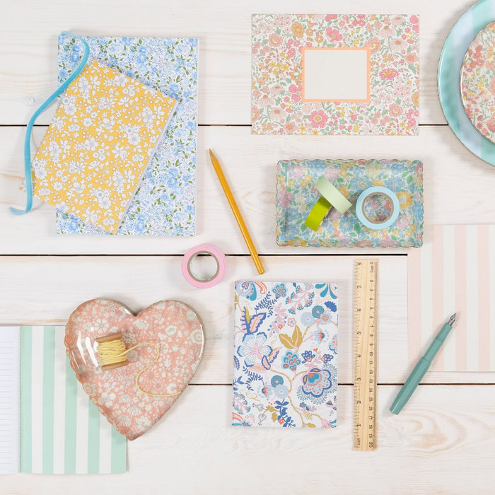 Assorted stationery items with floral patterns on a wooden surface