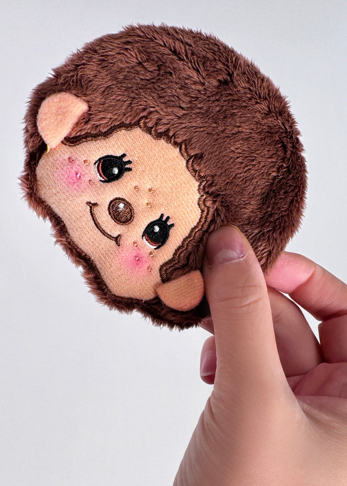 Sekiguchi Monchhichi-Kun Face Plush Coin Bag in brown with embroidered Monchhichi-Kun face and bell charm on soft plush kawaii coin bag — model view