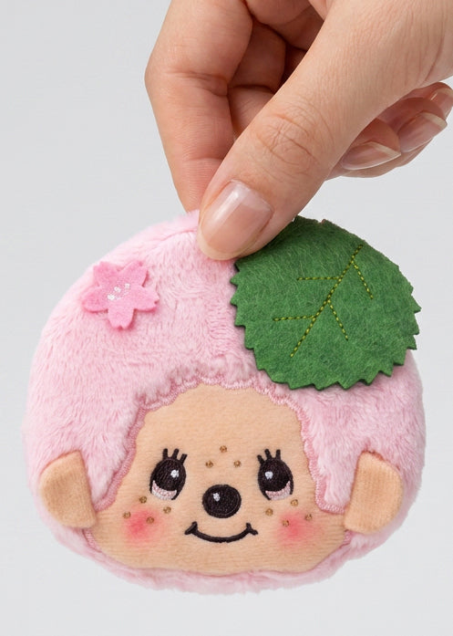 Sekiguchi Monchhichi-Kun Sakura Mochi Pink Plush Coin Bag held in hand showing sakura flower and green leaf detail — detail view