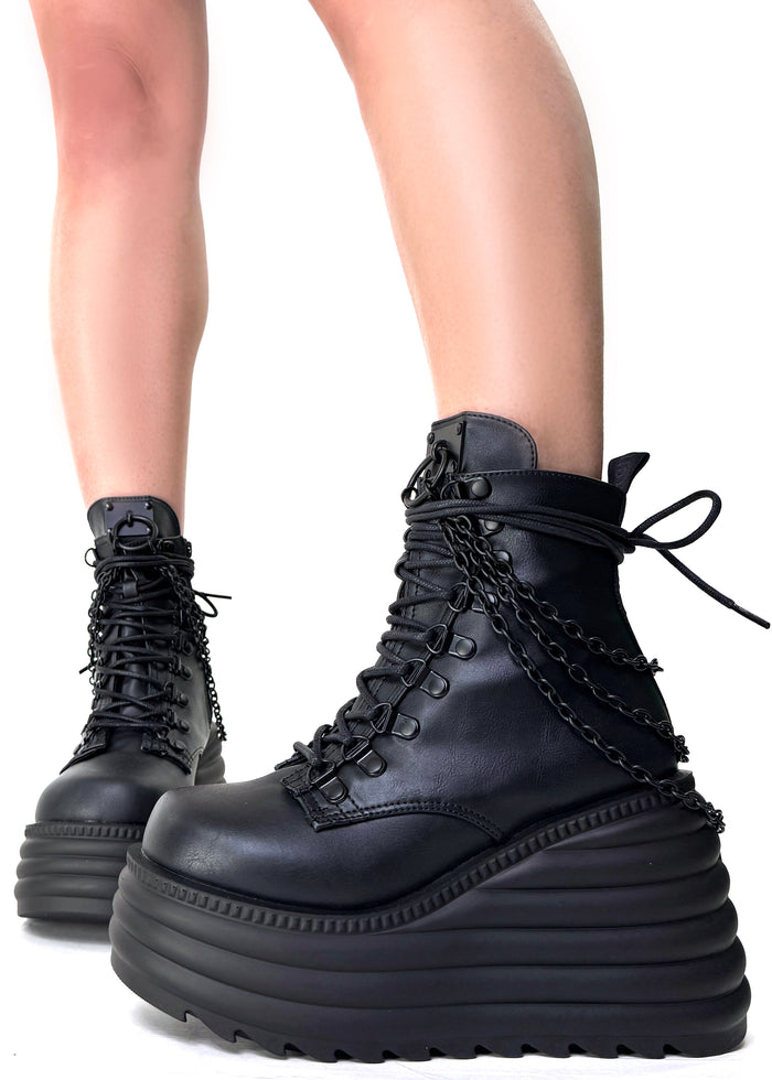 Demonia MORTE 65 Black Rave Platform Boots in black vegan leather with lace-up front and metal chain detail worn by model — side view