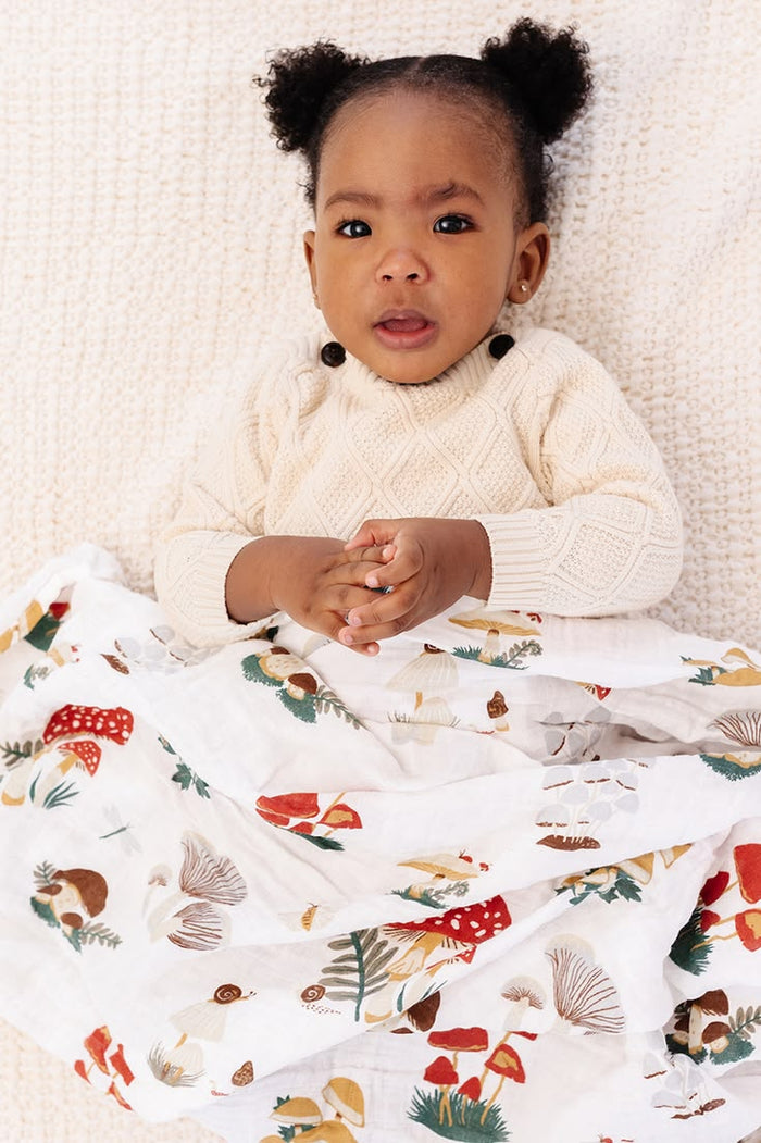 Child wrapped in a colorful blanket with a white knit blanket underneath