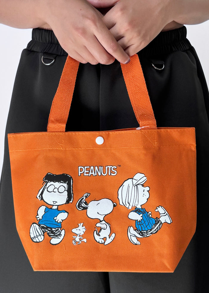Peanuts Snoopy and Friends Canvas Orange Lunch Tote in orange with Snoopy and friends graphic on durable canvas lunch tote bag — model view