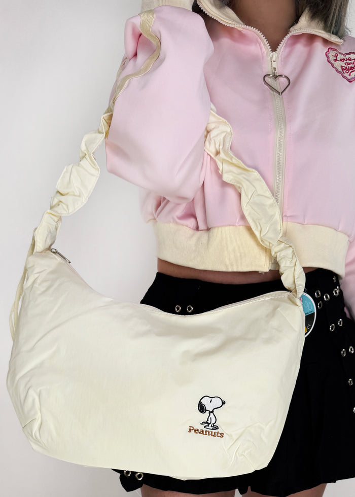 Peanuts Snoopy Classic Medium Nylon Ivory Shoulder Bag in ivory with Snoopy classic embroidery on water-resistant nylon shoulder crossbody bag — model view