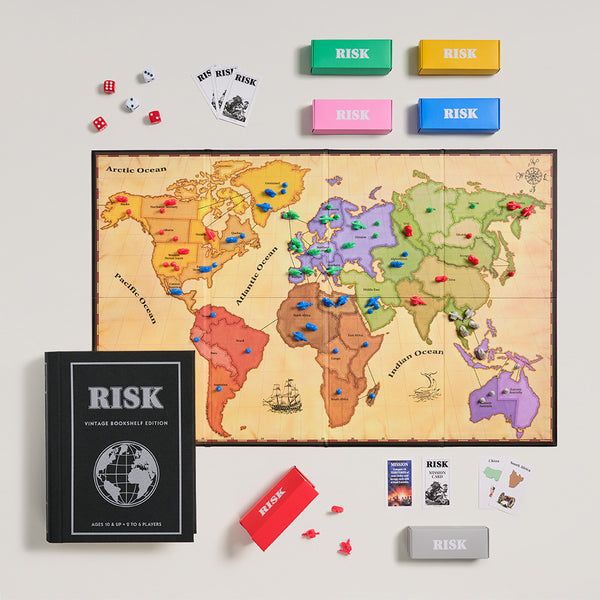 Risk board game set with world map, pieces, and book on a light gray background