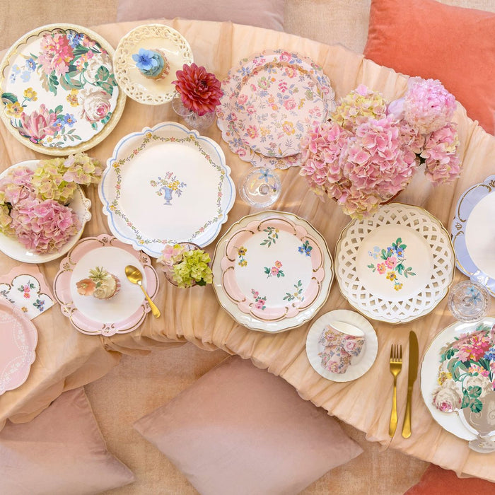 Decorative table setting with floral plates and flowers on a beige tablecloth.