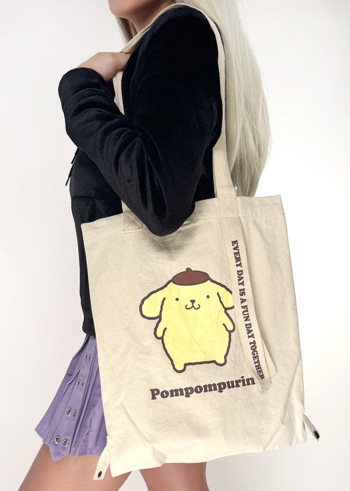 Sanrio Pompompurin Convertible Canvas Tote in yellow with Pompompurin print on 2-way convertible rave festival tote bag — model view