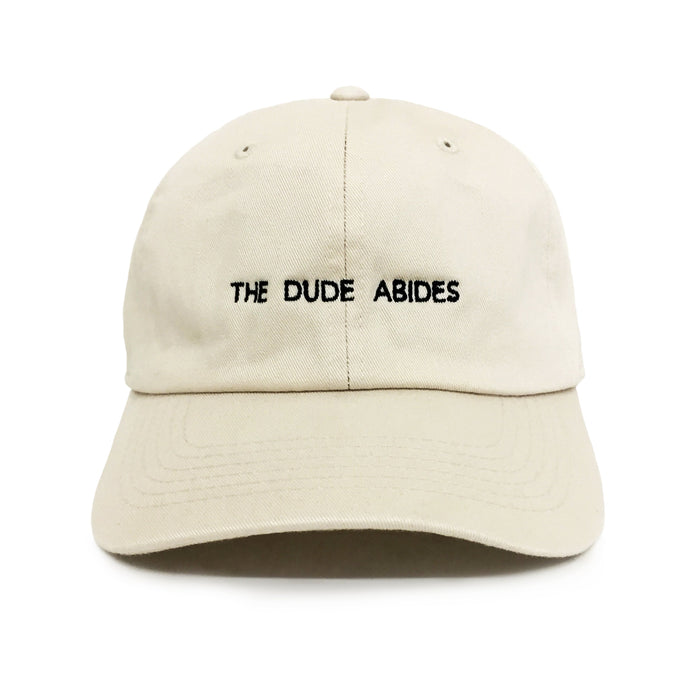 Beige cap with 'The Dude Abides' text on a white background