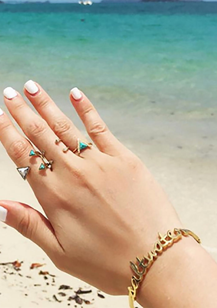 Wanderlust + Co Saltwater Bangle in gold with cursive saltwater script on 24k plated stainless steel hinged bangle bracelet — model view