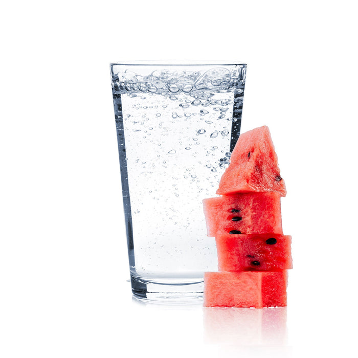 A glass full of Watermelon Hard Seltzer with watermelon slices next to the glass.